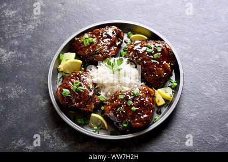 In prossimità della piastra con dolci e miele piccante grigliate di cosce di pollo con riso scuro sul tavolo di pietra. Foto Stock