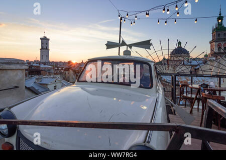 Lviv (Lwiw, Lemberg): Dim Lehend (casa di leggende), terrazza sul tetto, auto Trabant 601, bar, tetti della Città Vecchia, la torre del Municipio, persone in , Lviv Oblas Foto Stock