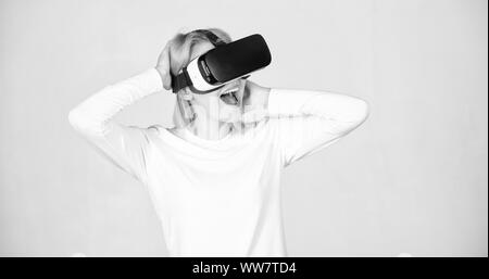 Stupiti giovane donna toccando l'aria durante l'esperienza di VR. Una persona in bicchieri virtuale mosche di spazio in camera. Donna eccitato usando 3d occhiali protettivi. Digital VR