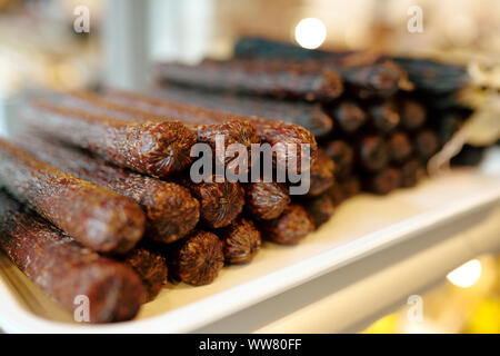 Pila di gustosa e piccante Salsiccia fresca in display con prodotti a base di carne Foto Stock