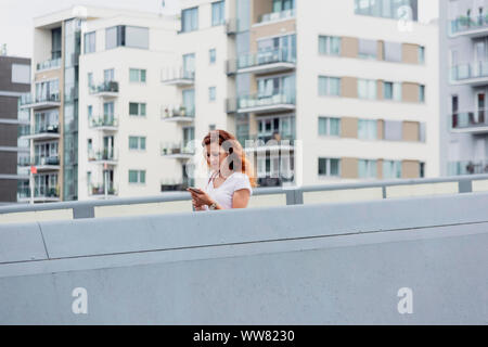 Giovane donna guardando smartphone Foto Stock