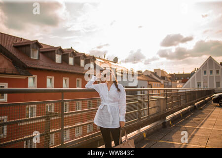 Giovane donna in camicia bianca in piedi e appoggiate su di recinzione Foto Stock