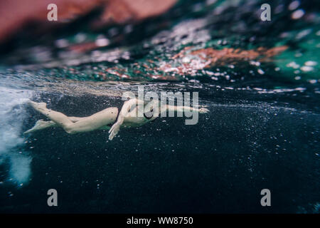 Per tutta la lunghezza della donna nuoto sott'acqua vicino a una vecchia barca Foto Stock