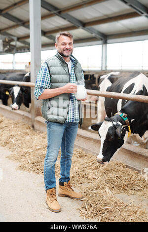 Un sano giovane agricoltore con brocca di latte nelle aziende lattiere Foto Stock