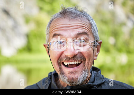 Close-up di una faccia di un piacere, o sorpresa uomo in bicchieri con una sottile cornice di metallo su un laccio indossando un piccolo batuffolo. Ritratto di un uomo intelligente Foto Stock