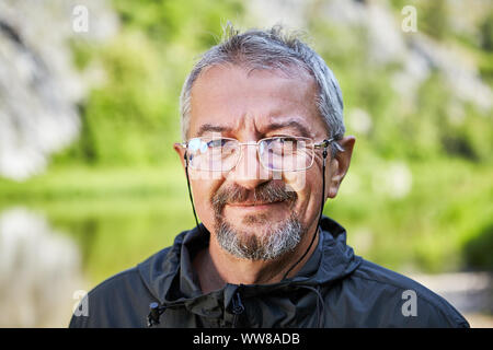 Ritratto di strada di un uomo istruito di etnia caucasica, 56 anni, con gli occhiali in una sottile cornice metallica e un piccolo batuffolo. La faccia intelligente Foto Stock