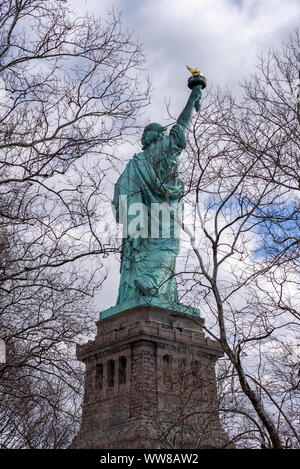 Indietro ritratto della Statua della Libertà incorniciata da rami di albero, New York City, Stati Uniti d'America Foto Stock