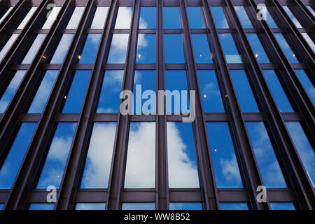 Basso angolo di vista di un moderno edificio con facciata di vetro e al di fuori di travi di acciaio con il cielo che riflette in Windows. Foto Stock