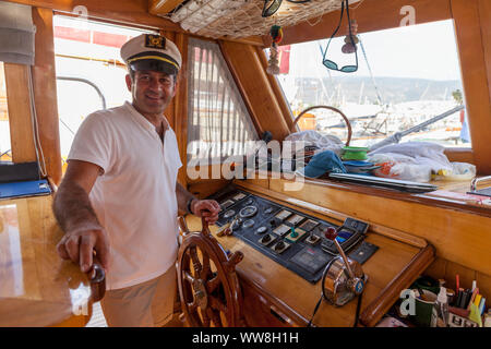 Capitano al volante su yacht e barche a vela mentre la barca è in porto bodrum, Turchia, Foto Stock