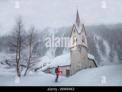 Sci touring davanti alla cappella del Santo Spirito sotto una nevicata, Kasern, Predoi, Valle Aurina, Bolzano, Alto Adige, Italia Foto Stock