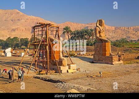 Area di Scavo con ricostruita colossali statue e paesaggio di montagna in Thebes-West, Luxor, Alto Egitto Egitto Foto Stock