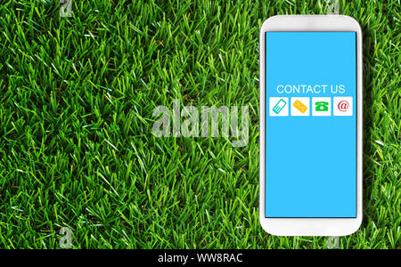 Sito web e internet contattaci concetto, customer service, telefono cellulare su erba verde sullo sfondo Foto Stock