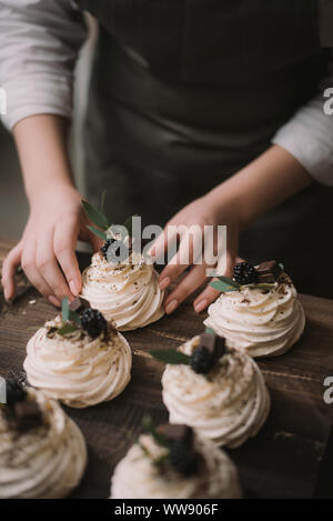 Pasticcere crea un matrimonio dessert. Ragazza raccoglie dessert da meringa, cioccolato e frutti di bosco Foto Stock
