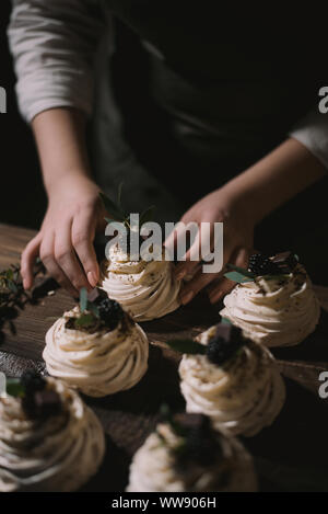 Pasticcere crea un matrimonio dessert. Ragazza raccoglie dessert da meringa, cioccolato e frutti di bosco Foto Stock