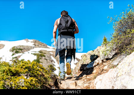 Uomo di arrampicata in montagna rocciosa sul Linkins Lago trail sull indipendenza passa vicino Aspen Colorado a inizio estate del 2019 con la neve Foto Stock