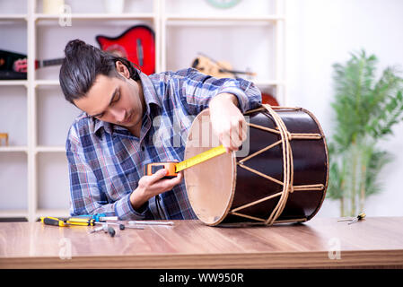 Il giovane bello repairman riparazione di tamburo Foto Stock