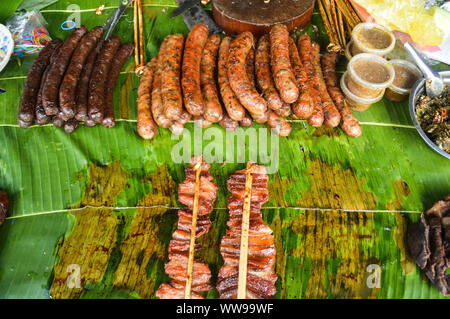 Salsiccia di Lao o sou oa, pollo alla griglia o ping gai, e Lao barbecue o sindad venduto come cibo di strada tradizionale al mattino Luang Prabang Foto Stock