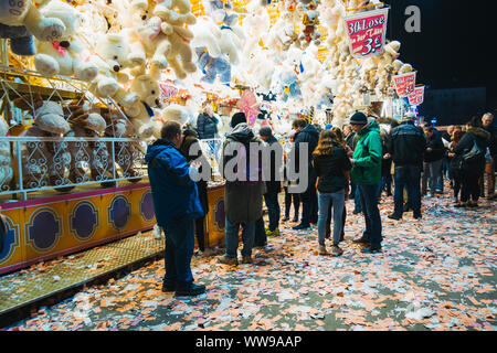 Decine di giocattolo animali appendere al di sopra di una lotteria-come il gioco mentre i partecipanti alla fiera a piedi passato una notte a una fiera di Amburgo, Germania Foto Stock