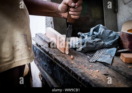 Le mani del falegname con uno scalpello nelle mani sul banco di lavoro in falegnameria Foto Stock