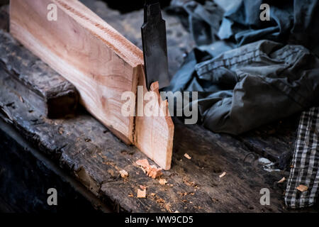 Le mani del falegname con uno scalpello nelle mani sul banco di lavoro in falegnameria Foto Stock