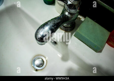 Vecchio lavello rubinetto di acqua nel buio Foto Stock