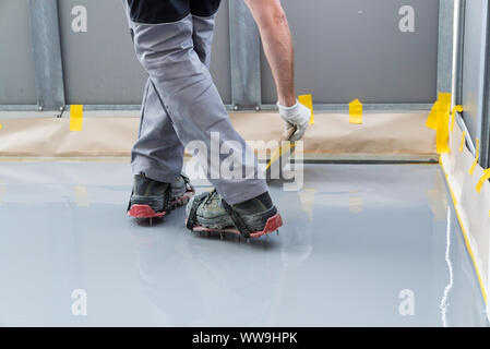 Un lavoratore edile rinnova il balcone piano e si diffonde a tenuta stagna e resina collante prima di chipping e la chiusura a tenuta Foto Stock