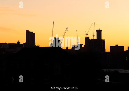 Silhouette di Leeds skyline durante il sunrise. Yorkshire il nuovissimo edificio più alto "Altus House' è in costruzione tra gli altri edifici di nuova costruzione. Foto Stock