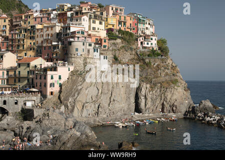 Manarola, Italia - Luglio 2, 2018: le case colorate di Manarola villaggio di pescatori luogo salire al di sopra di mare i bagnanti e barche su un caldo a metà giornata estiva ho Foto Stock