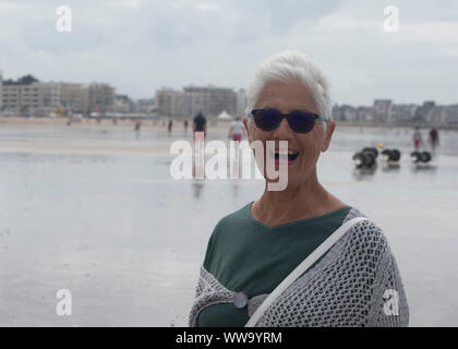 Una donna anziana sulla spiaggia Foto Stock