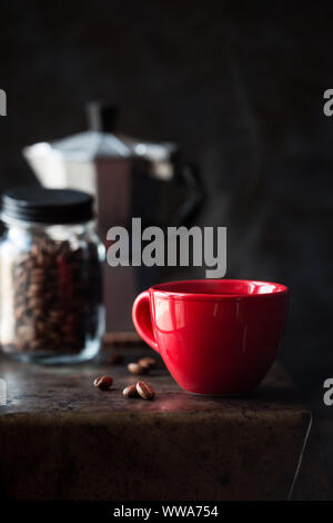 Red tazza di caffè contro uno sfondo scuro. Buona mattina concetto Foto Stock