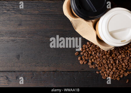 Carta per due tazze di caffè in tazza di supporto e i chicchi di caffè scuro su un tavolo di legno. Un caffè di buona qualità Foto Stock