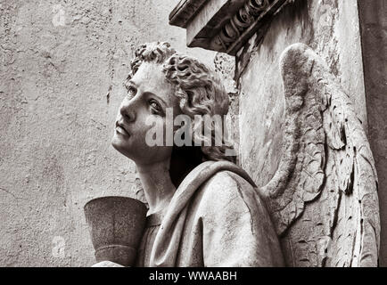 Weathered statua di pietra di angelo nel cimitero. Foto Stock