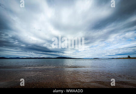 Drammatico il cielo sopra il bello acqua calma nel Golfo di Botnia. Storsand, Costa Alta nel nord della Svezia. Foto Stock