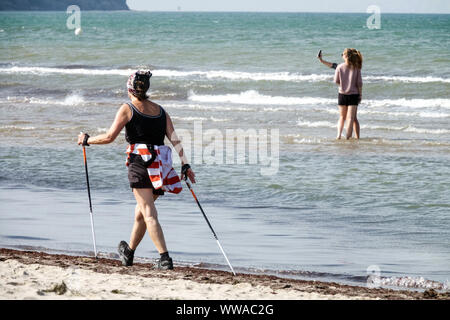 Donna anziana nordic Walking lungo la spiaggia Mar Baltico Germania invecchiamento attivo Foto Stock