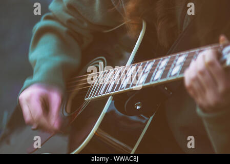 Vicino la donna con le mani in mano suonare la chitarra acustica con la sensazione del movimento della mano Foto Stock