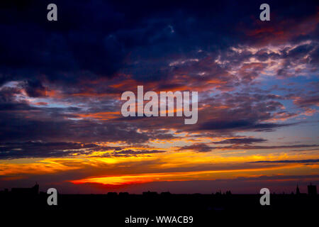 New Scenic 5 posti è vista sul bel cielo azzurro con soffici nuvole al tramonto e il paesaggio urbano in distanza. Foto Stock