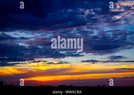 New Scenic 5 posti è vista sul bel cielo azzurro con soffici nuvole al tramonto e il paesaggio urbano in distanza. Foto Stock