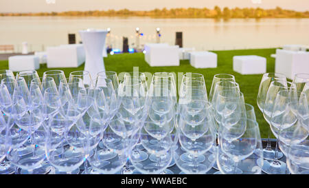 Un sacco di bicchieri di vino in una fila. Occhiali di lusso per l'alcool. Bicchieri di vino con vino su un tavolo esterno. Foto Stock