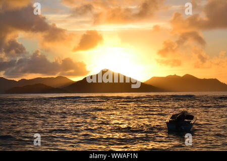 Seychelles tramonto dietro l'Isola di Praslin. Vista da La Digue Island. Foto Stock