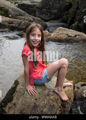 Holiday snap di 9 anno vecchia ragazza seduta su di una roccia in Scozia Foto Stock