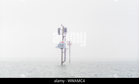 Un marcatore è quasi avvolta nella nebbia in acque pericolose fuori Skåtøy. Il marker ha segnali acustici come pure la luce. Foto Stock