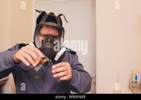 Il Tecnologo in bianco tuta protettiva con retina per capelli e maschera e lavorando in cibo e bevanda fabbrica. L'uomo specialista controllo bottiglie per prodotto di bevanda Foto Stock