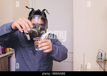 Il Tecnologo in bianco tuta protettiva con retina per capelli e maschera e lavorando in cibo e bevanda fabbrica. L'uomo specialista controllo bottiglie per prodotto di bevanda Foto Stock