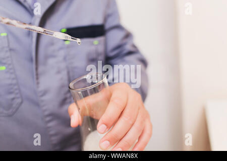 Il Tecnologo in bianco tuta protettiva con retina per capelli e maschera e lavorando in cibo e bevanda fabbrica. L'uomo specialista controllo bottiglie per prodotto di bevanda Foto Stock