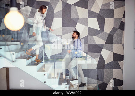 Popolo sorridente a piedi fino alla scalinata in azienda Foto Stock