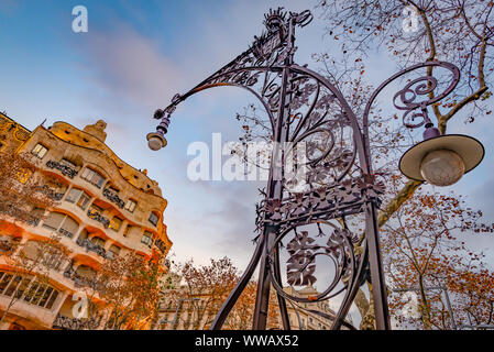 Ampio angolo di vista di un luce di ornati post con Casa Mila (La Pedrera) in background, Barcellona, Spagna Foto Stock