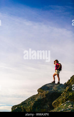 Giovane donna escursionismo con uno zaino sulla cima di Mt. Mansfield, Stowe Vermont, USA