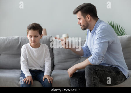 Padre arrabbiato scolding triste kid figlio per cattivo comportamento Foto Stock