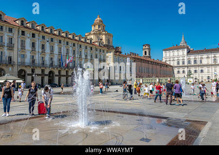 I bambini giocano nelle fontane di Piazza Castello, una piazza importante della città in una calda giornata estiva a Torino Foto Stock