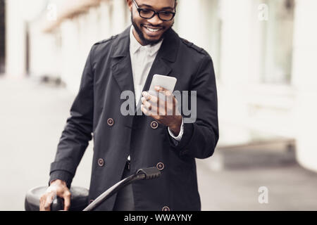 Giovane uomo elegante texting sul telefono in piedi vicino a bike Foto Stock